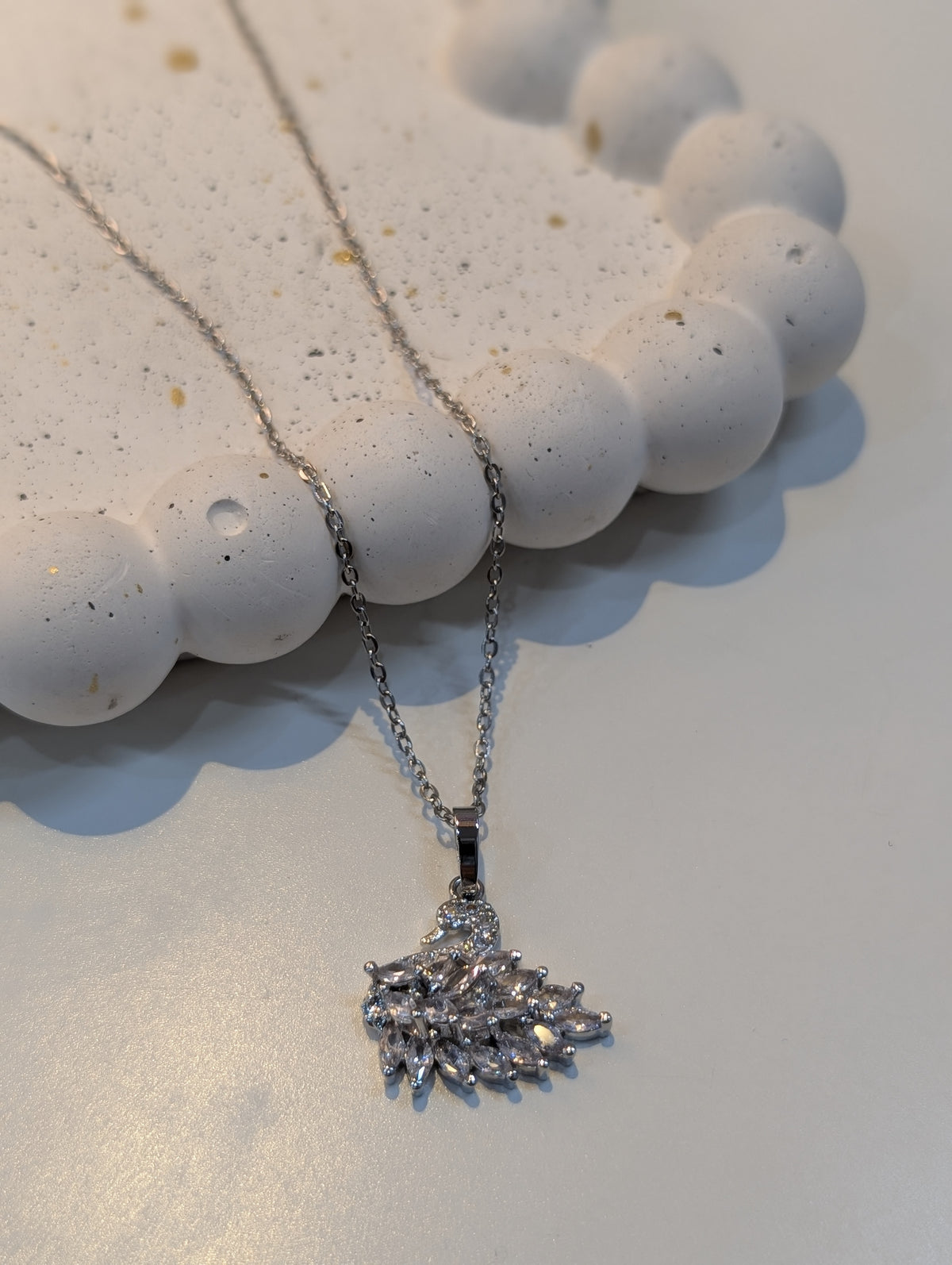 A silver-tone chain necklace with a pendant made of clustered clear, faceted stones in an abstract, spiky design.