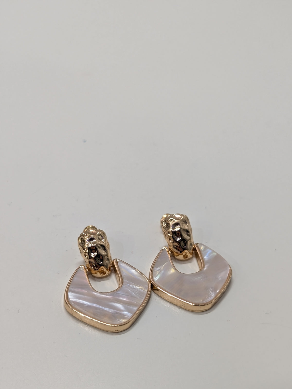 Earrings with a textured gold-tone top and a rounded-square drop edged in gold-tone, containing a pale pearlescent pink-white inset.