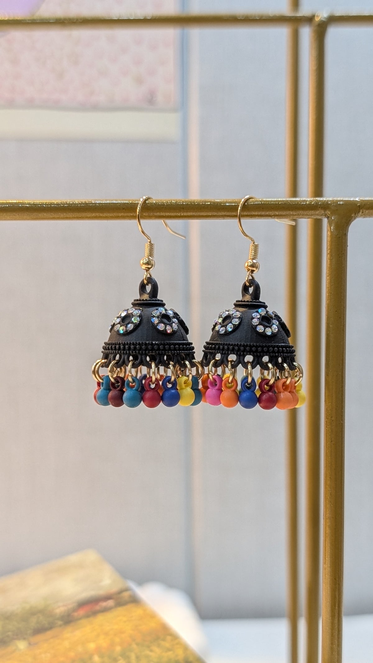Pair of black dome-shaped dangle earrings with gold-tone hooks, clear circular accents, and a fringe of small colorful beads.