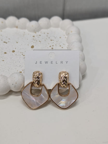 Gold-tone drop earrings with textured tops and open geometric frames around pearly iridescent white inserts.
